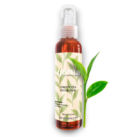 Bottle of green tea hydrosol with a label and leaves on a white background